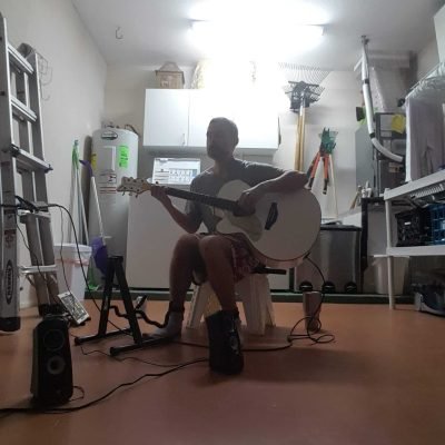 Ryan May sitting in a garage in Jupiter, Florida playing guitar.