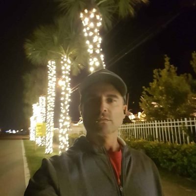 Ryan May standing near Jupiter Marina with Christmas lights on palm trees in Jupiter, Florida.