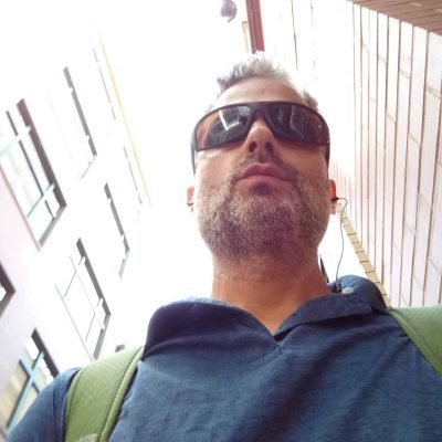 Ryan May walking through Pittsburgh wearing sunglasses and a backpack.
