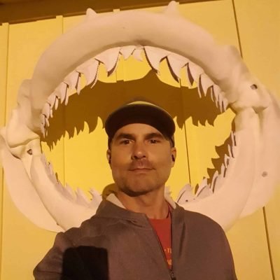 Ryan May standing in front of the shark jaw display at Sea Treasures in Jupiter, Florida.